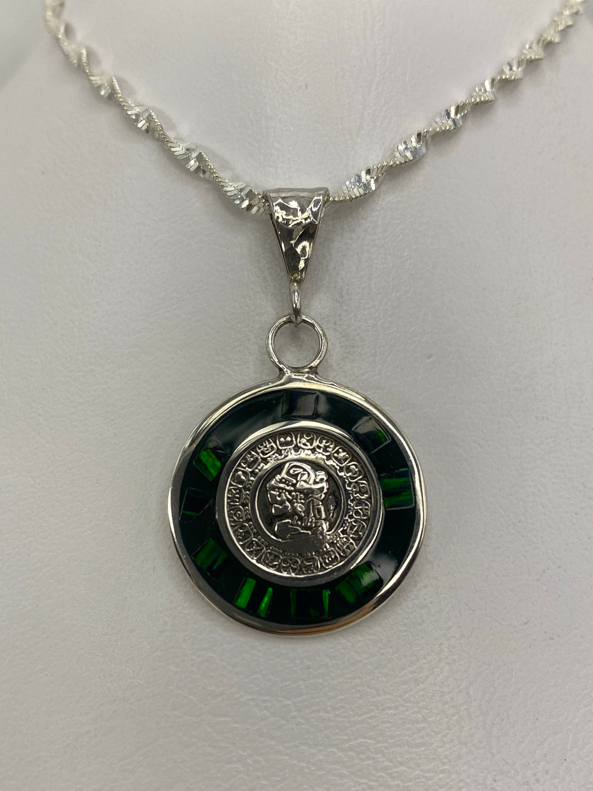 Detalle del calendario azteca grabado en el dije de plata, con ópalo verde engastado en el centro
