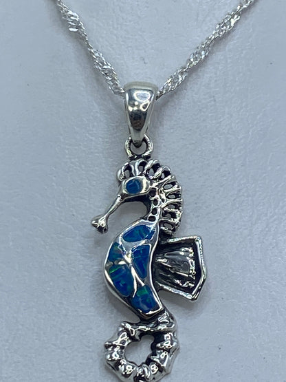 Dije caballito de mar en plata 950 con ópalo de fuego azul, sobre cadena plateada