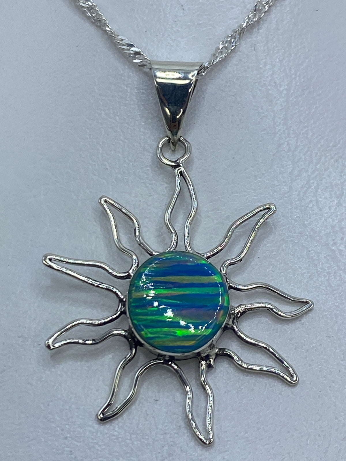 Dije de plata 925 en forma de sol con ópalo de fuego azul en el centro