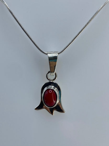 Detalle cercano del coral rojo redondo engastado en el centro del tulipán de plata 925
