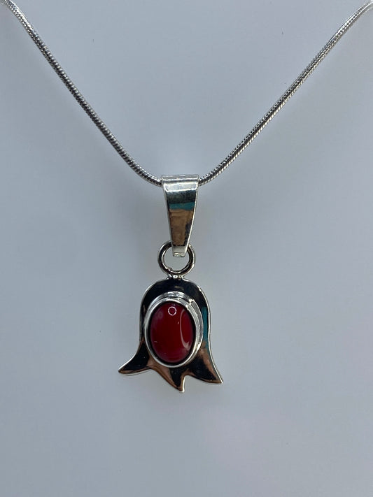 Detalle cercano del coral rojo redondo engastado en el centro del tulipán de plata 925