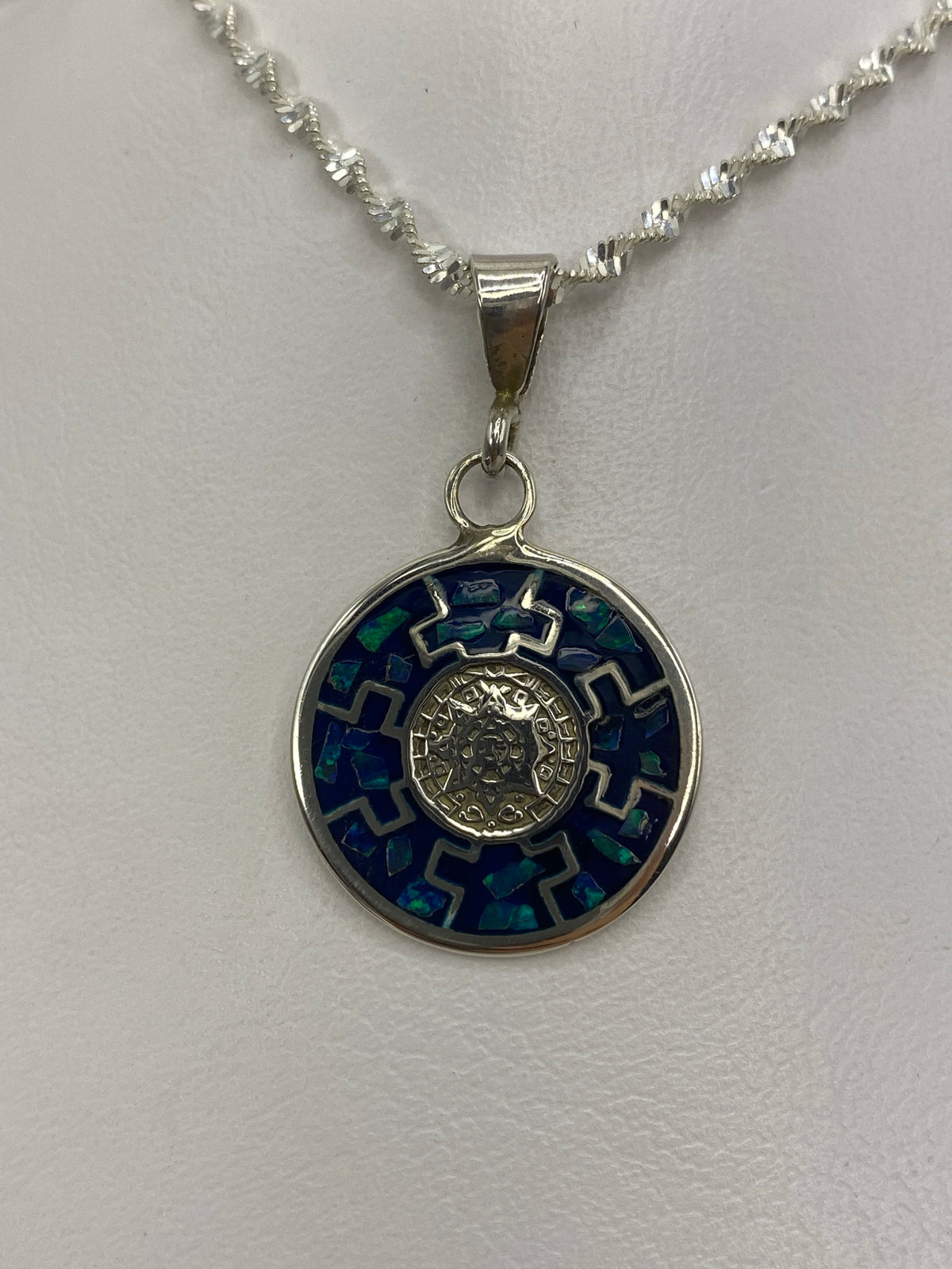 Dije de plata con calendario azteca y Ópalo de Fuego azul colgando de cadena plateada
