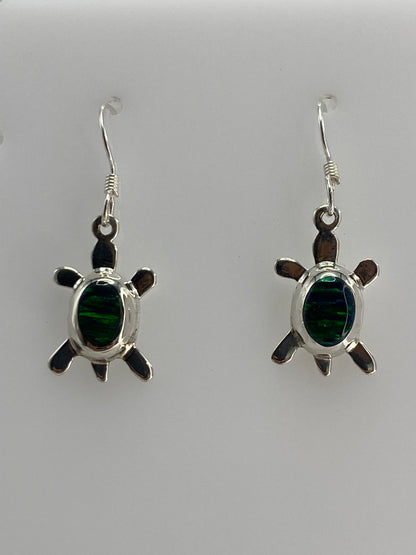 Detalle de arete de tortuga con ópalo verde engastado en plata, vista frontal