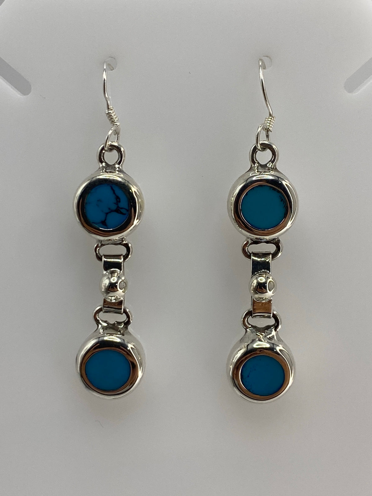 Detalle frontal de los aretes mostrando la turquesa azul y el engaste a mano en plata 925