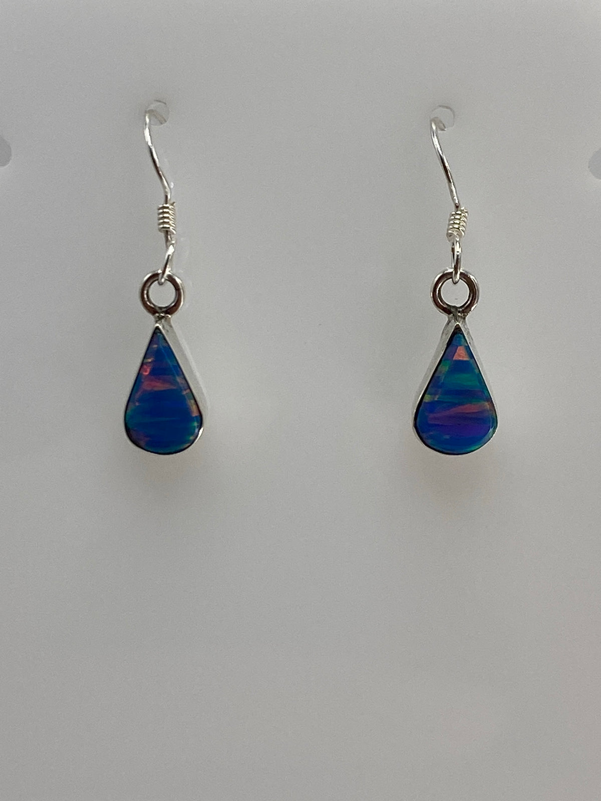 Detalle del ópalo de fuego azul en el arete, mostrando las vetas de color iridiscente