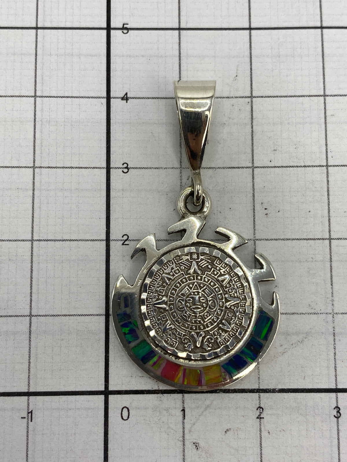 Dije sobre fondo blanco con medidas de 4 cm de largo × 2 cm de ancho