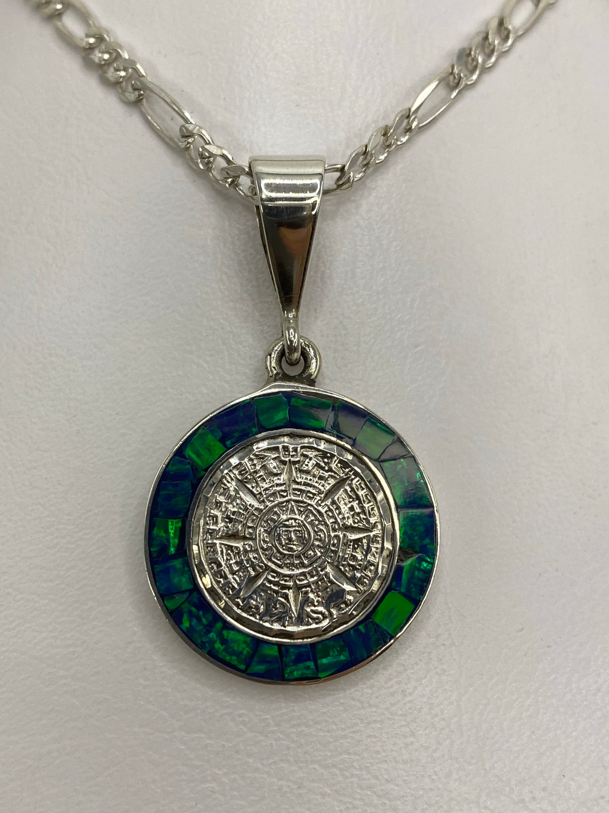 Dije de plata con calendario azteca en relieve y opalo de fuego azul en la cadena