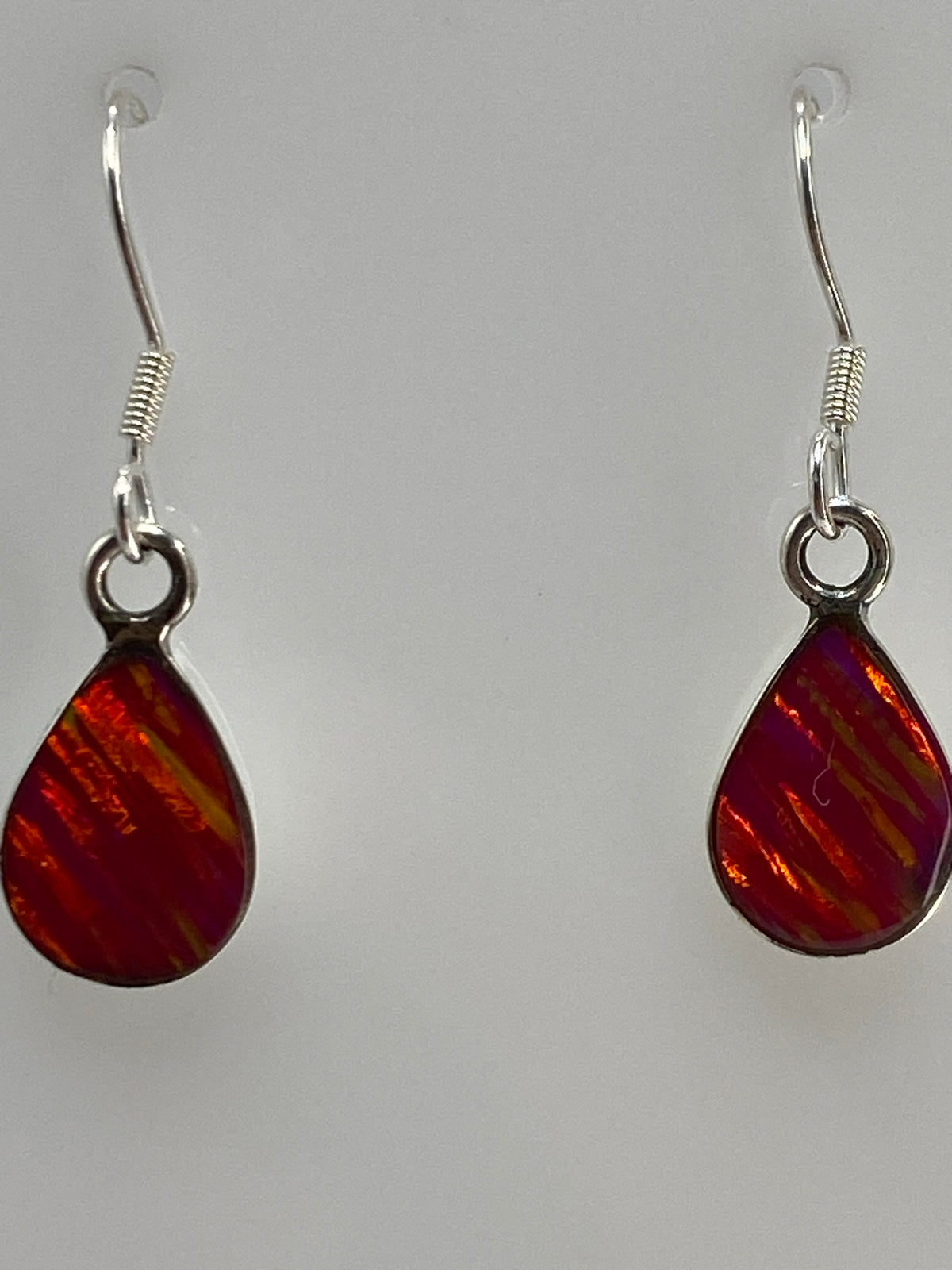 Aretes en las orejas, ópalo de fuego reflejando luz