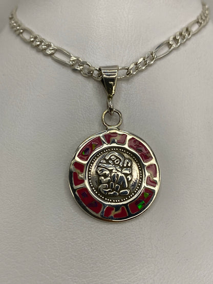 Dije de plata con motivo prehispánico y ópalo de fuego rosa, colgando de cadena figaro