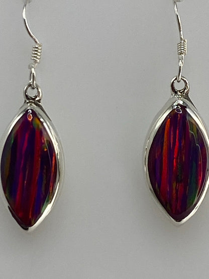 Aretes de ópalo multicolor sobre fondo blanco mostrando los reflejos dorados y rojos