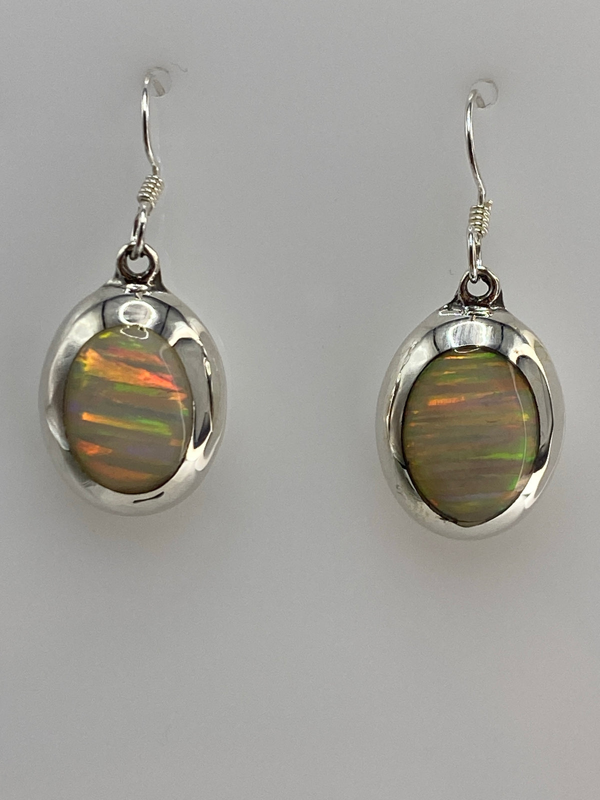 Aretes de plata con ópalo de fuego multicolor en fondos grises