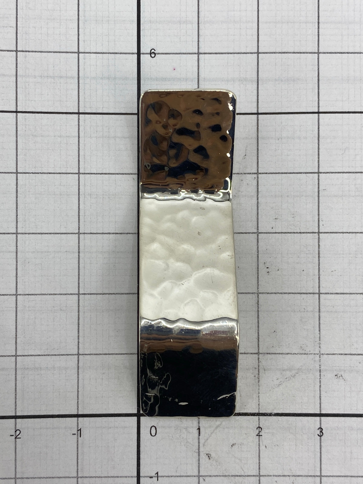Dije sobre escala de milímetros mostrando dimensión exacta de 5.5 × 1.5 cm