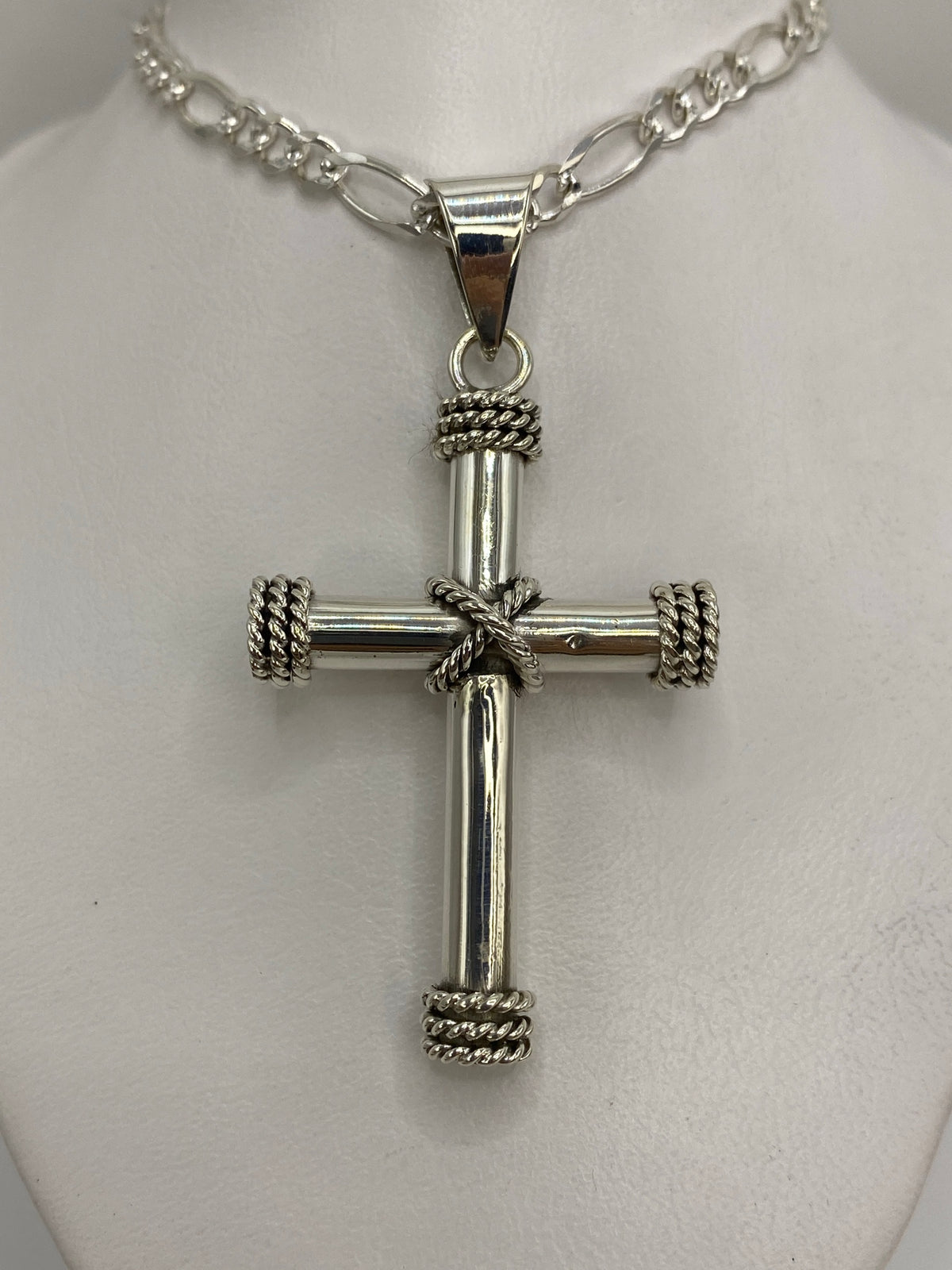 Cruz de plata taxco con detalle trenzado sostenida en mano, tamaño real 6 cm de largo