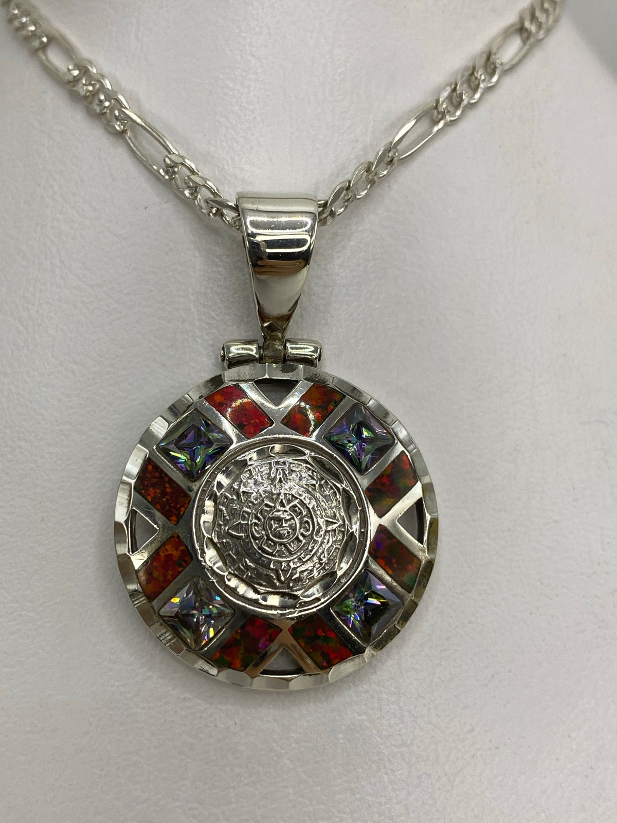 Dije Piedra del Sol en plata 950 con ópal de fuego rojo en el centro, rodeado de detalles prehispánicos