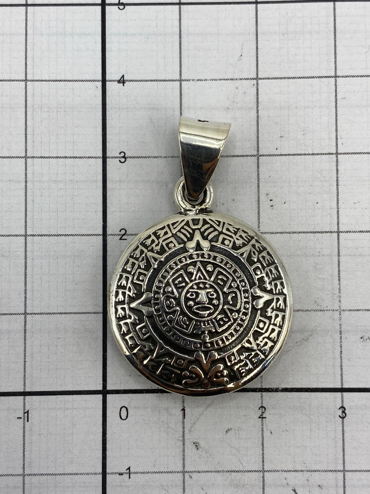 Dije sobre escala mostrando 3.4 cm de largo por 2.3 cm de ancho, plata 925 pura