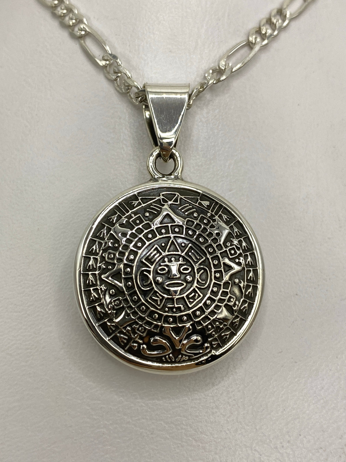 Dije de plata 925 con diseño del Calendario Azteca, grabado con símbolos prehispánicos, sobre cadena figaro