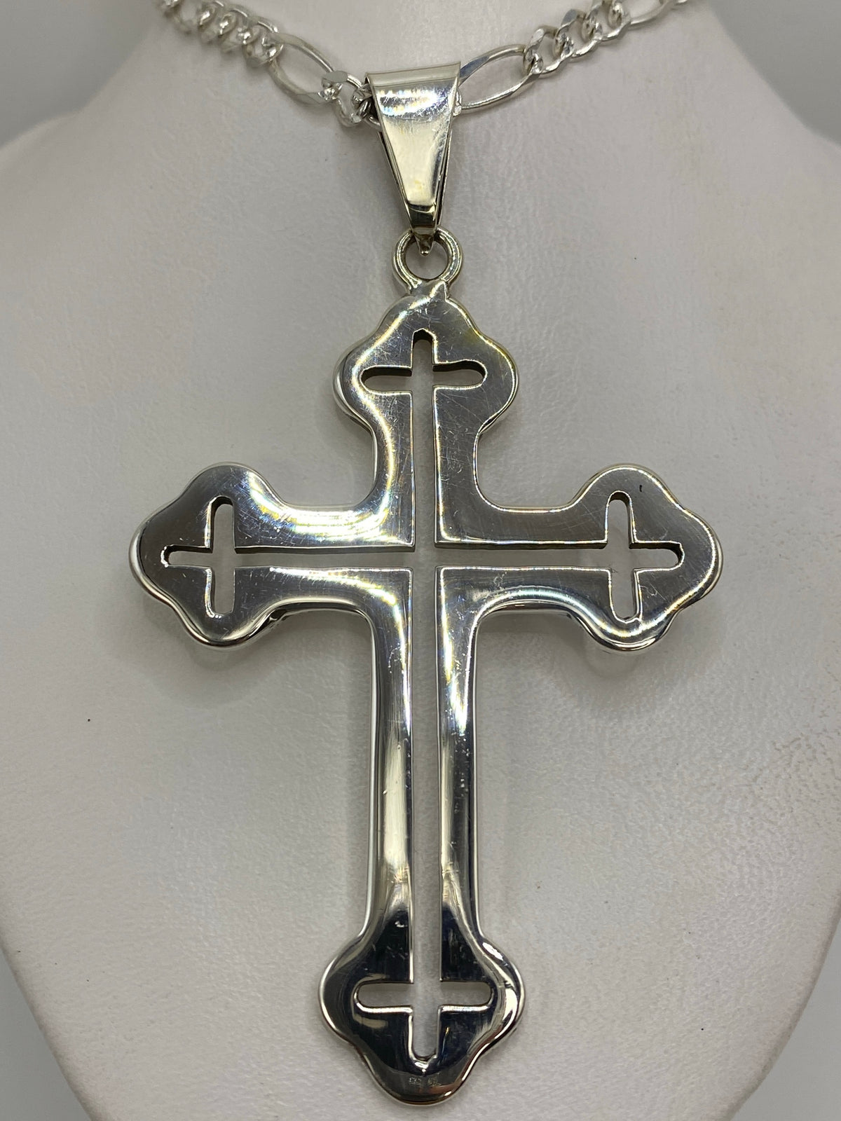 Dije cruz de plata 925 de Taxco con brazos curvados sobre fondo blanco