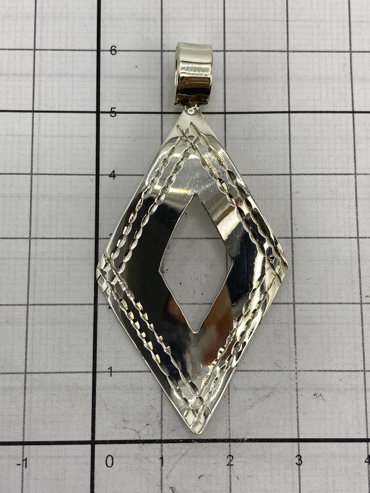 Dije sobre papel milimetrado mostrando medidas: 6 cm largo × 3 cm ancho