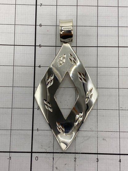 El dije de plata sobre una regla mostrando los 6 cm de largo y 3 cm de ancho