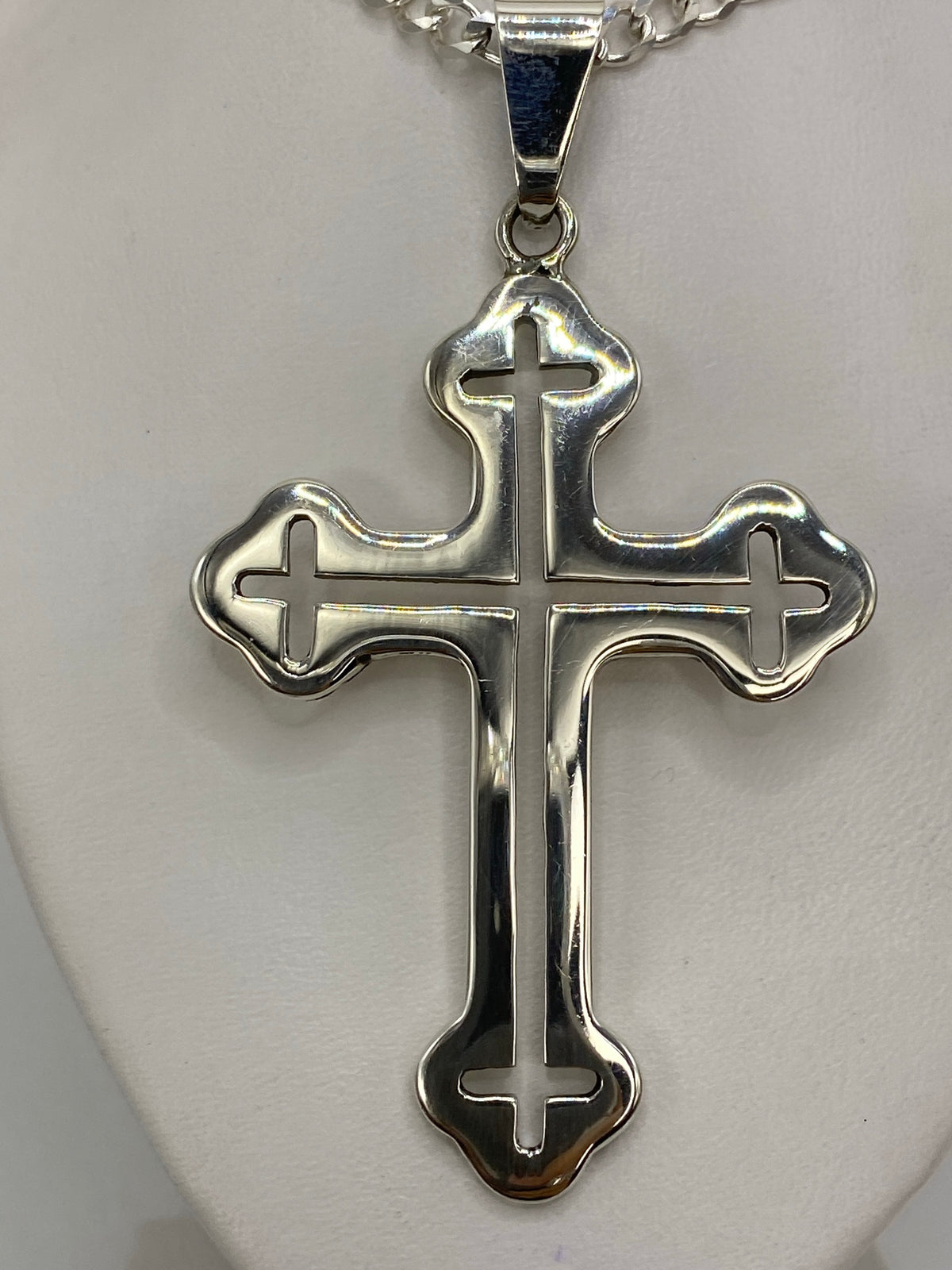 Cruz de plata 925 sobre regla en centímetros, midiendo 8 cm de largo