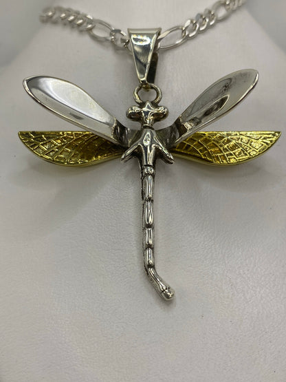 Detalle frontal del dije libélula mostrando las alas laminadas en oro y el cuerpo en plata pulida