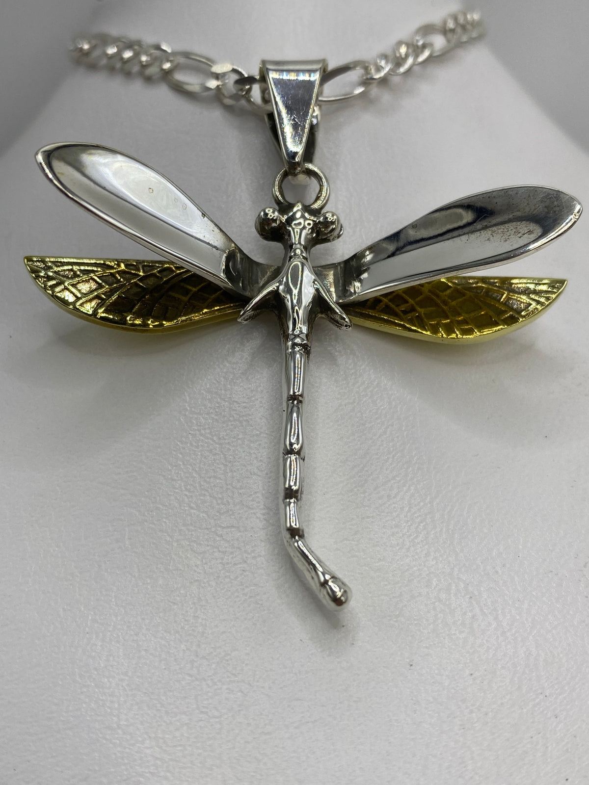 Detalle lateral del dije libélula mostrando el volumen repujado del cuerpo en plata Taxco