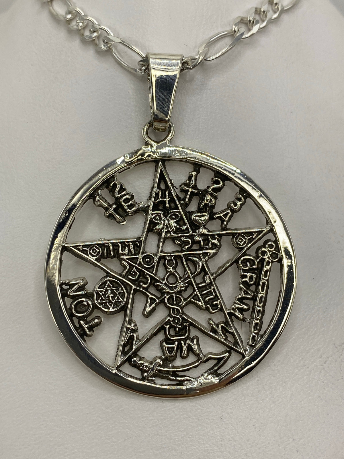 Dije pentáculo de plata 925 con símbolos místicos grabados, mostrando el diseño calado y el círculo central