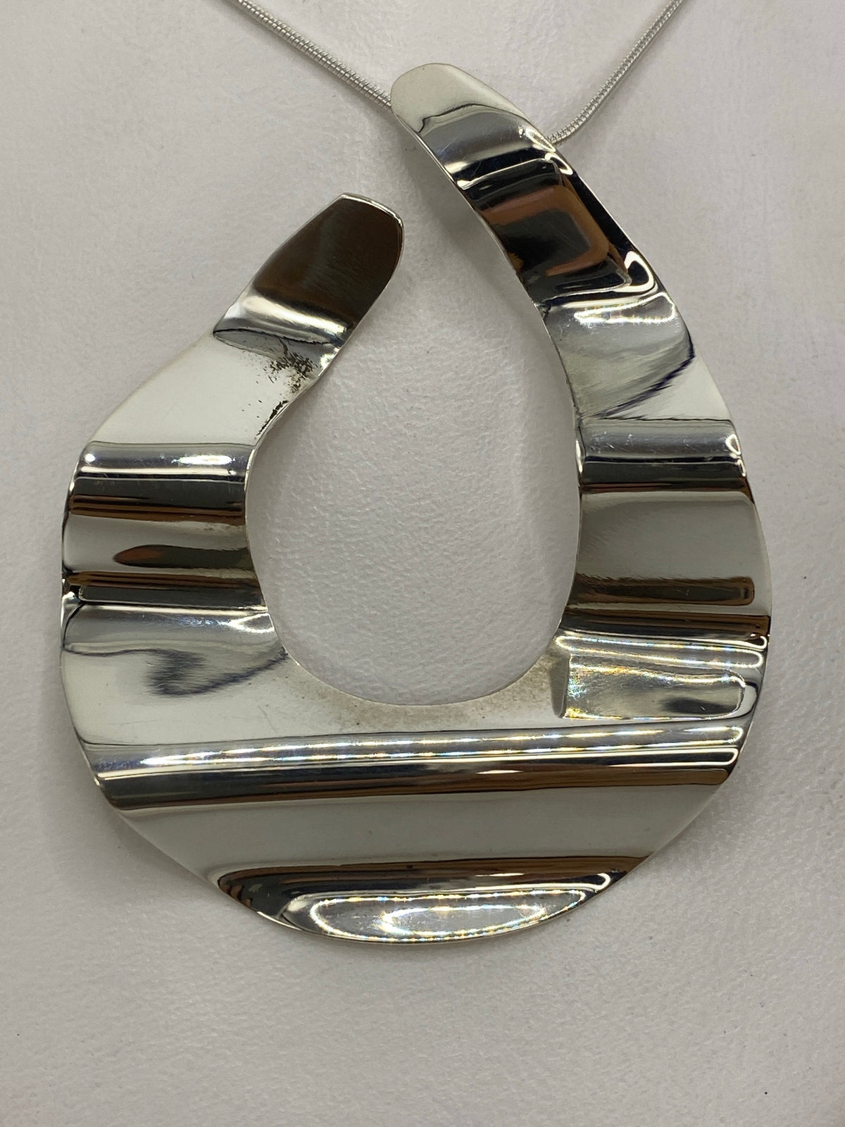Dije geométrico en vista frontal con medidas de largo 5.5 cm × ancho 4.5 cm