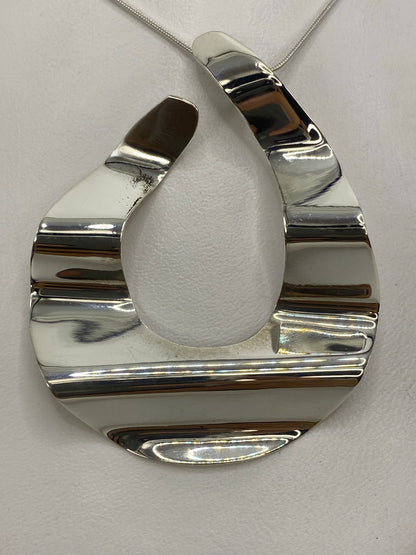 Dije geométrico en vista frontal con medidas de largo 5.5 cm × ancho 4.5 cm