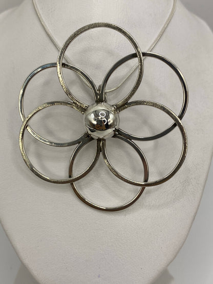 Dije floral de plata 925 con cinco pétalos en diseño geométrico, puesto sobre pecho