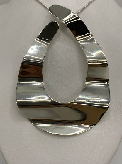 Dije de plata geométrico facetado colgando de cadena plateada