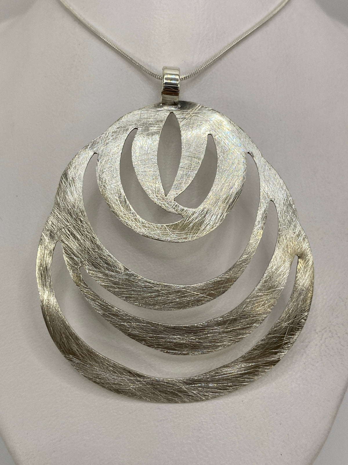 Dije de plata 925 con diseño escalonado en capas, acabado textil y pulido, colgando de cadena de plata