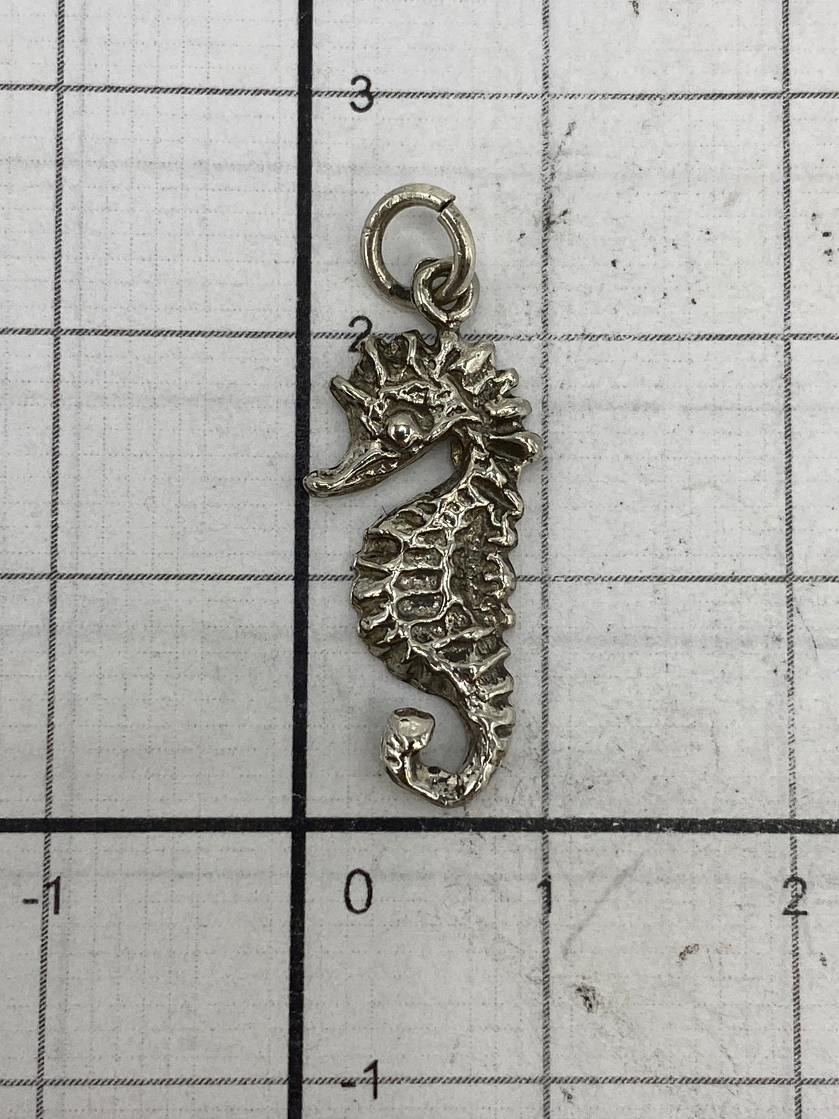 Caballito de mar de plata 925 en escala de medida, demostrando su tamaño compacto de 2.3 cm
