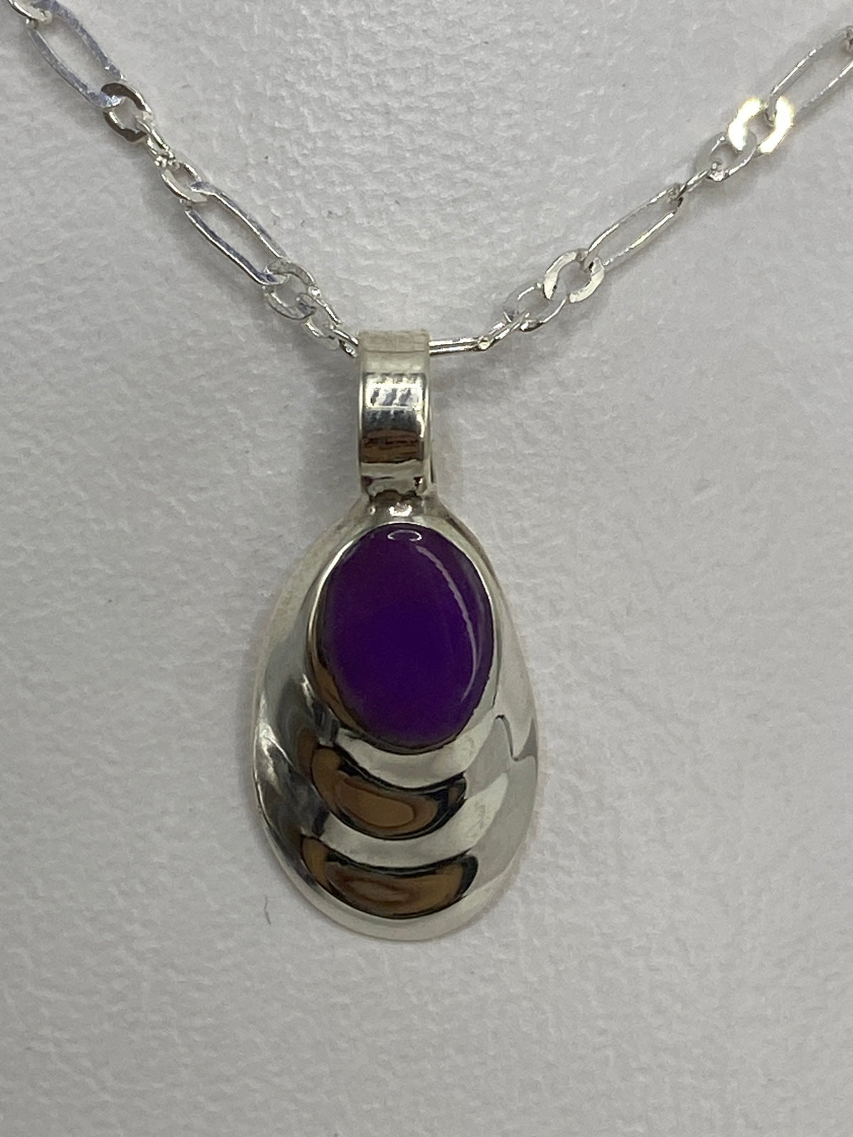Dije de plata 925 con piedra morada engastada, largo 2 cm, sobre cadena delgada
