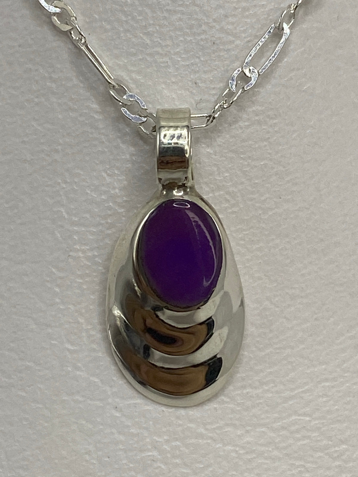 Dije de plata Taxco con piedra morada sobre regla, mostrando sus 2 cm de largo