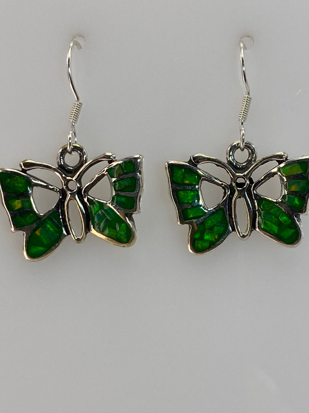 Aretes puestos en oreja, color verde del ópalo de fuego brillando a la luz natural
