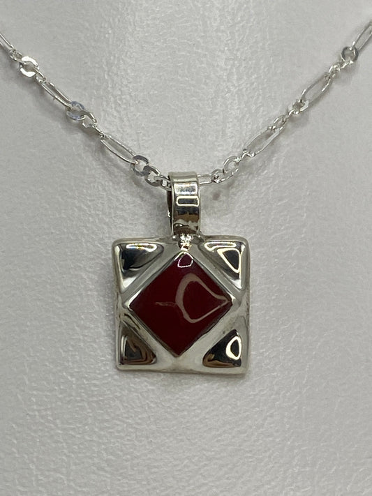 Dije de plata 925 con piedra roja engastada, colgando de cadena plateada