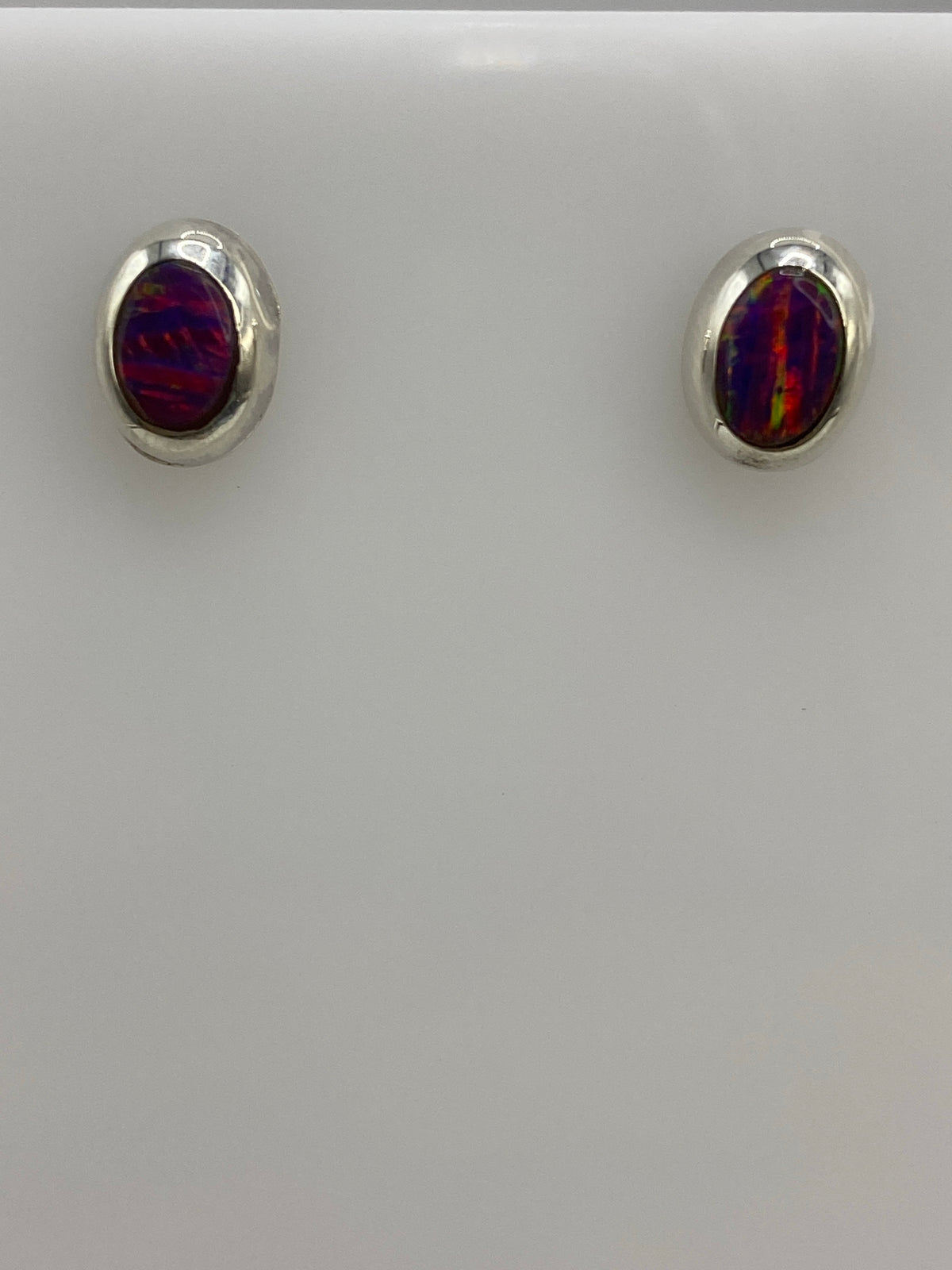 Par de aretes de plata 925 con ópalo de fuego morada, vistos de frente sobre fondo blanco