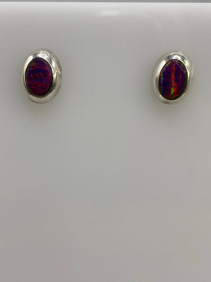 Par de aretes de plata 925 con ópalo de fuego morada, vistos de frente sobre fondo blanco
