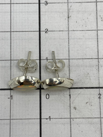 Aretes de plata Taxco con ópalo blanco sobre fondo neutro mostrando el Quinto