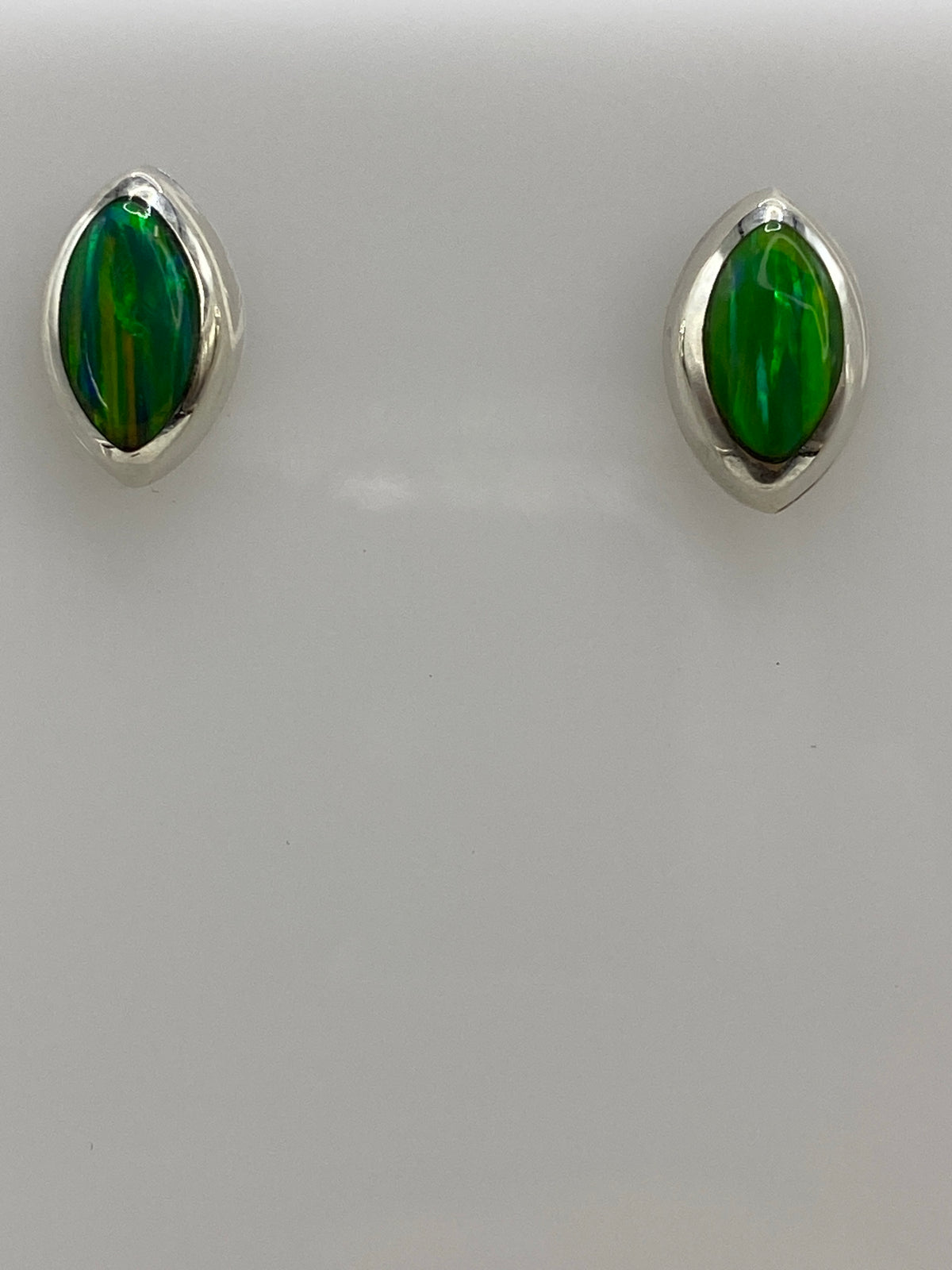 Aretes de ópalo de fuego sobre escala de referencia, mostrando tamaño real de 1.4 × 1 cm