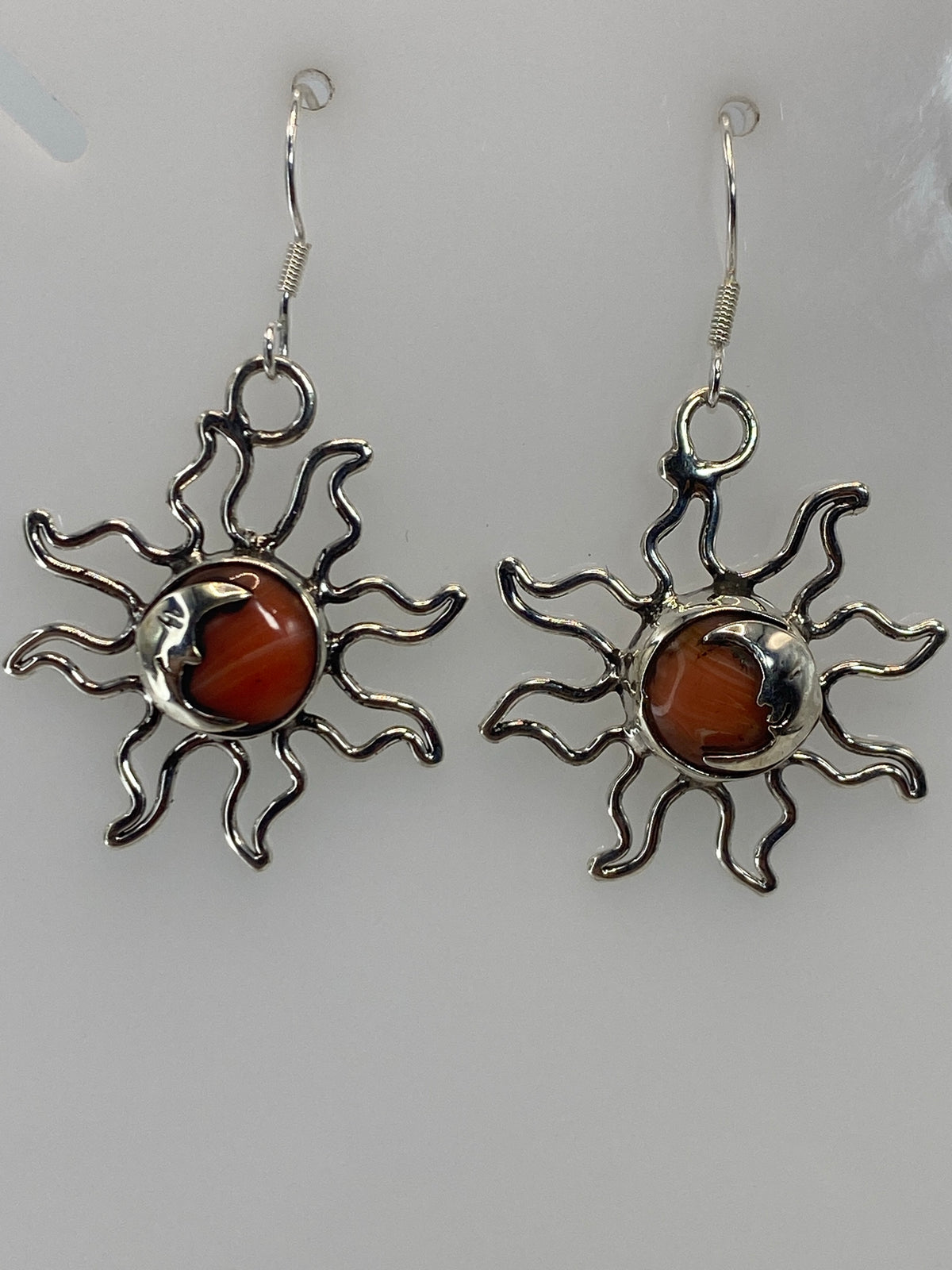 Detalle frontal de arete sol en plata 925 con coral engastado