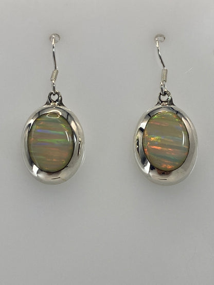 Aretes de ópalo mostrando el juego de luz naranja, rojo y verde dentro de la piedra