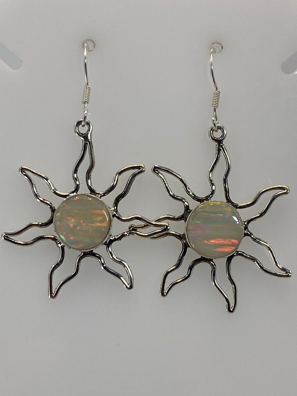 Par de aretes sol de plata 950 con ópalo de fuego naranja y verde, colgando sobre fondo blanco