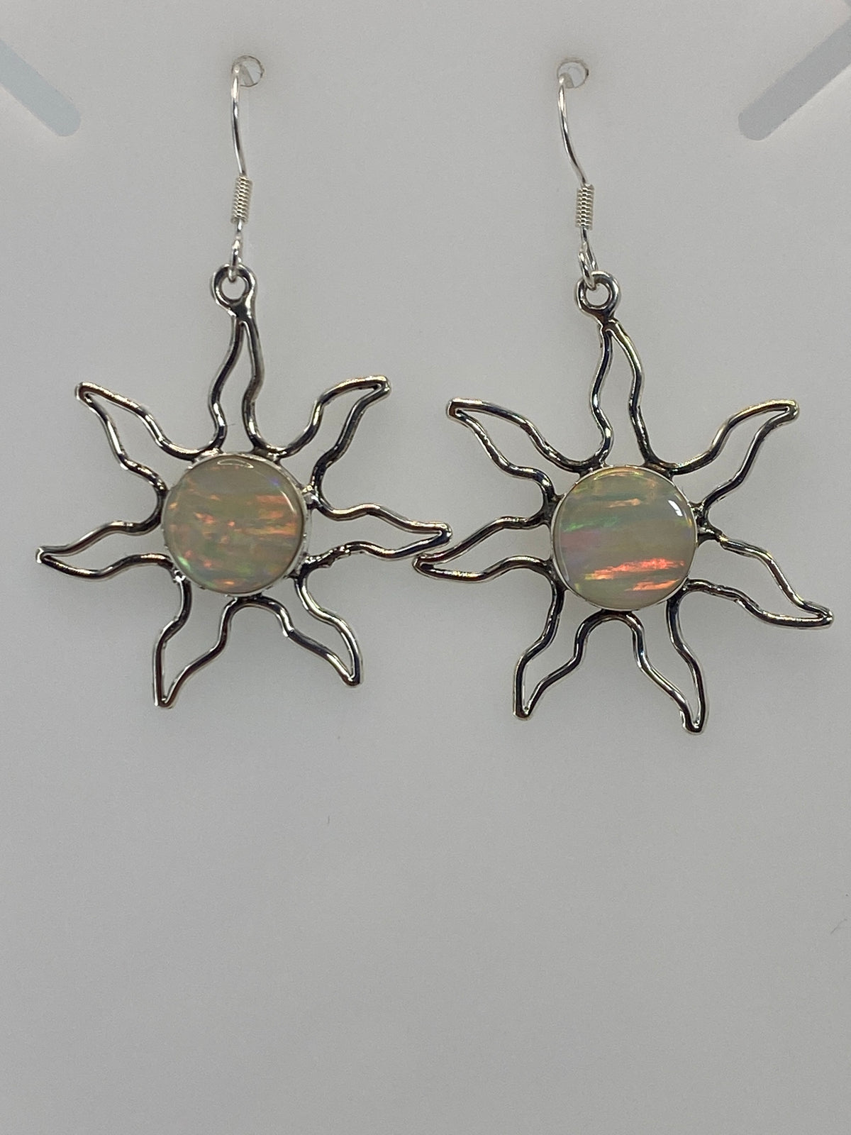 Detalle frontal de un arete sol mostrando el ópalo de fuego engastado en el centro y los rayos curvos de plata