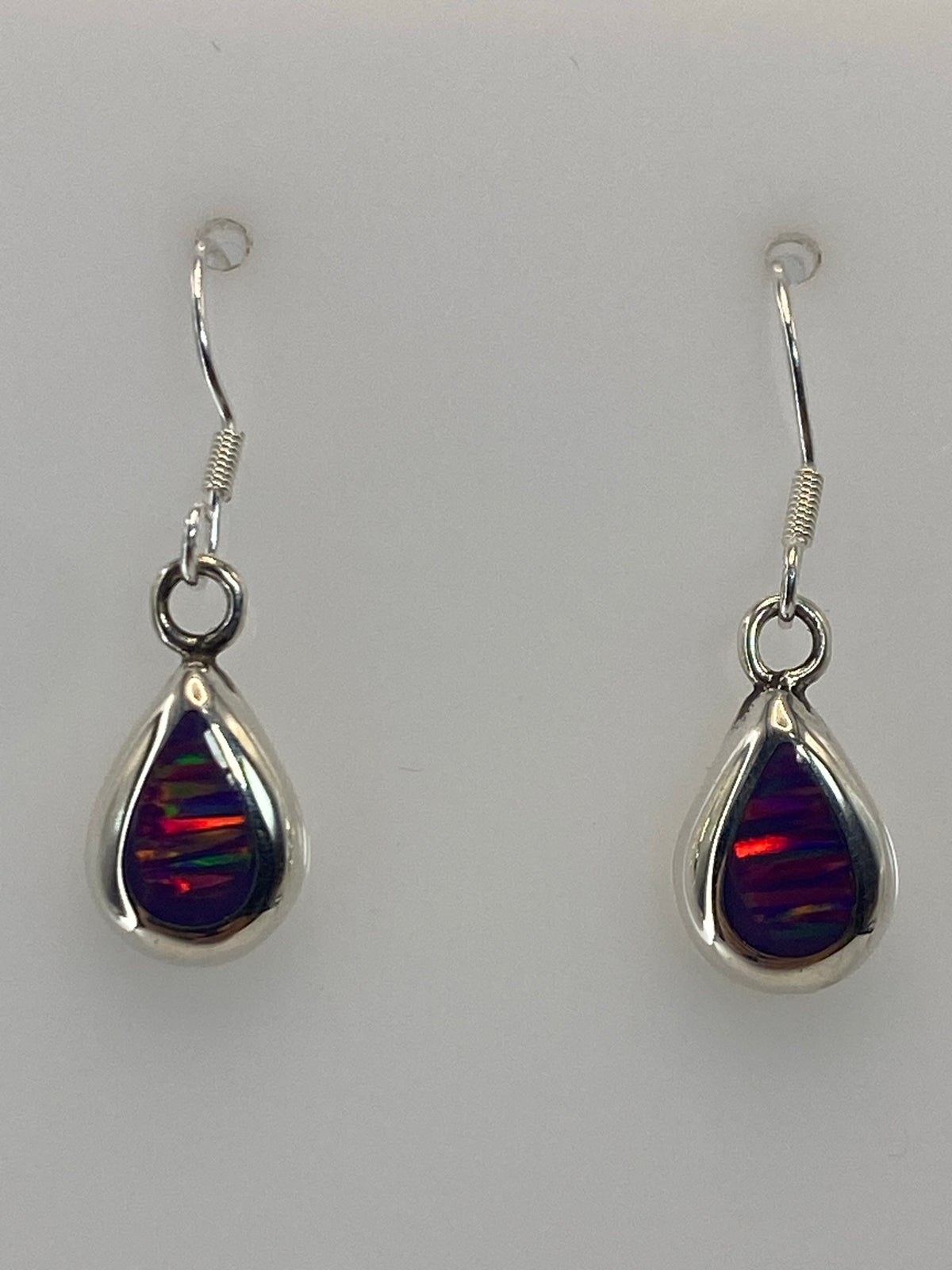 Par de aretes de plata con ópalo de fuego morado, gancho plateado, sobre fondo blanco