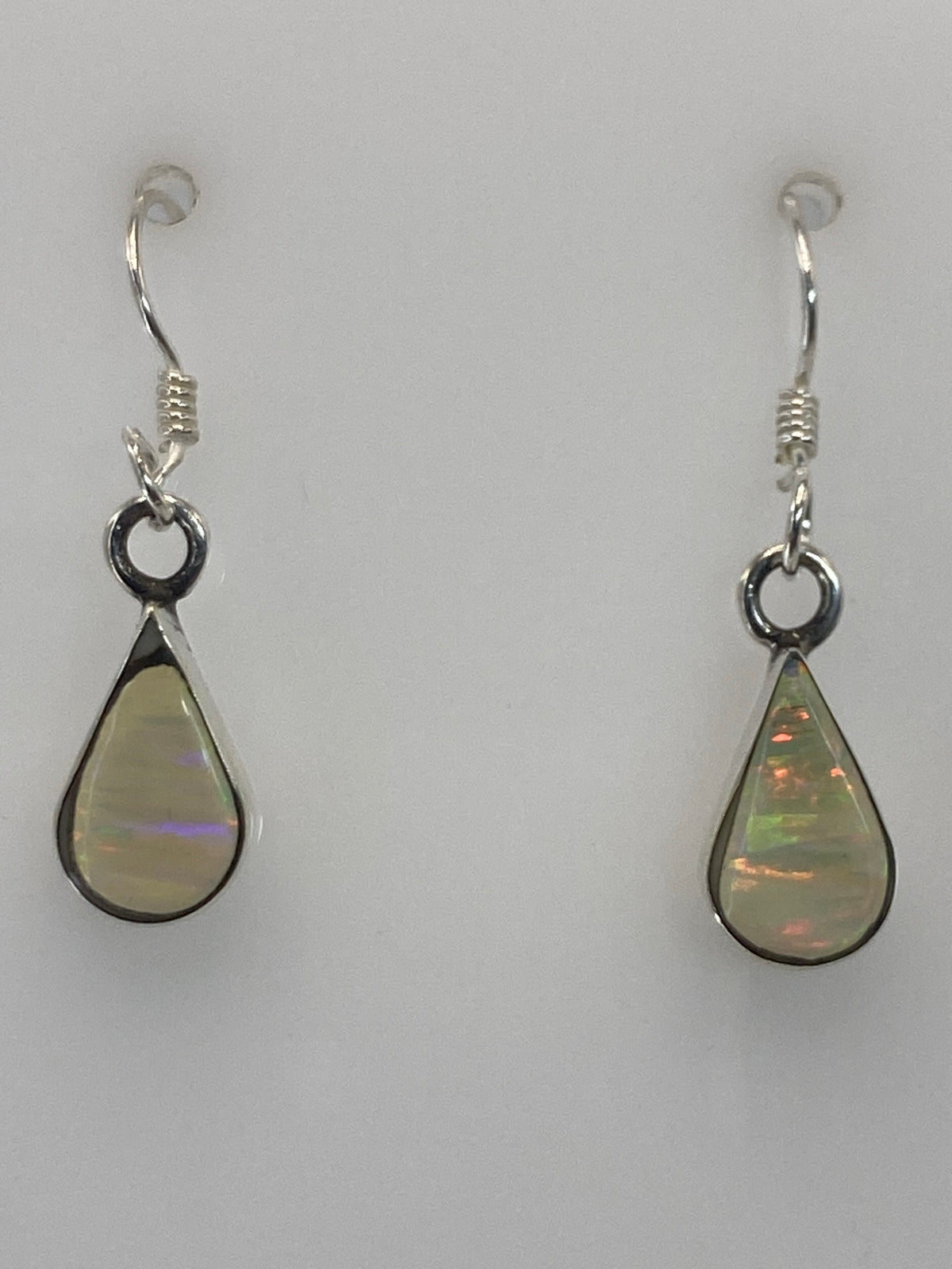 Par de aretes de plata 950 con ópalo de fuego en gancho, mostrando los destellos rojos y naranjas de la piedra