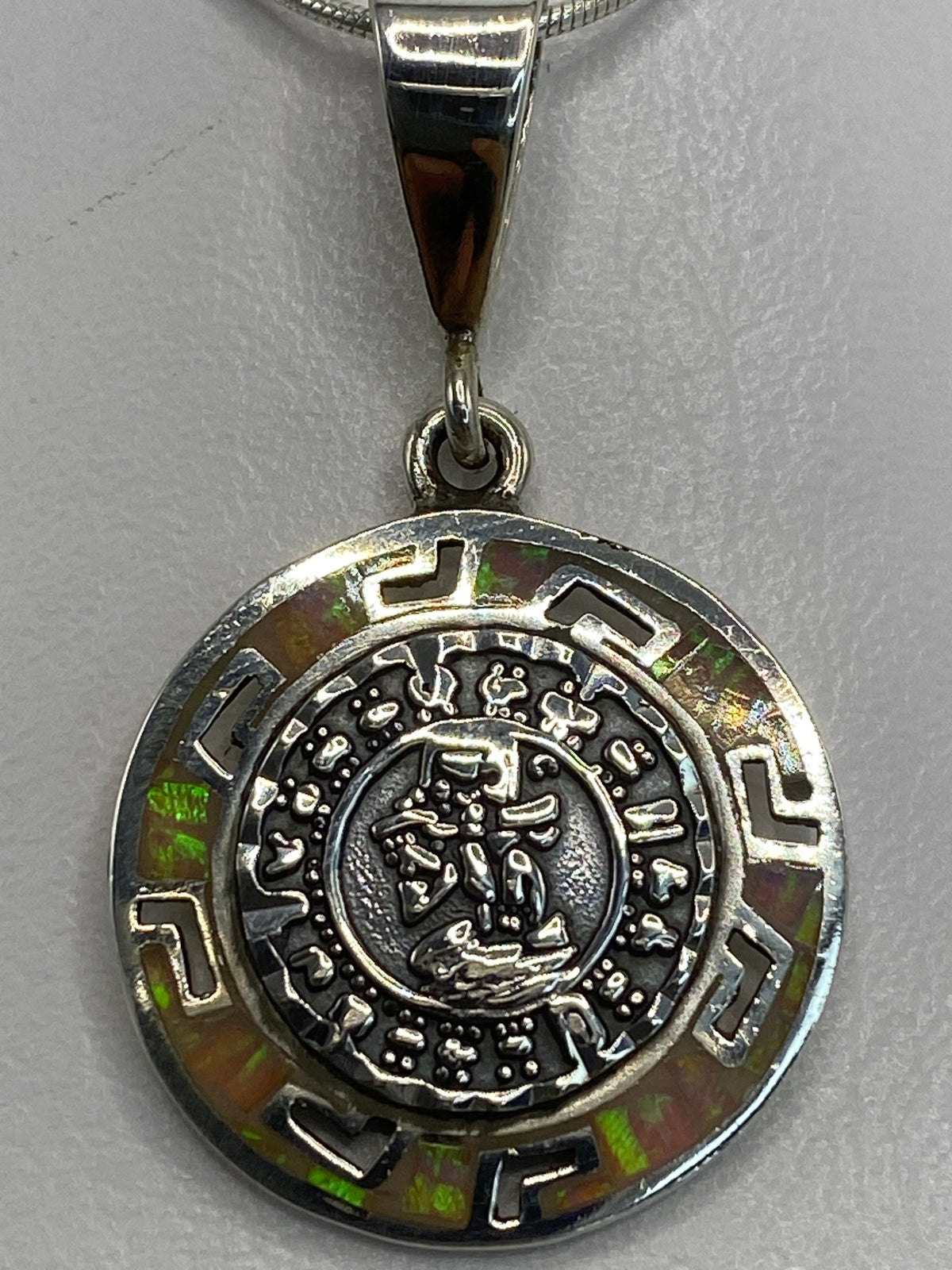 Dije de plata 950 sobre fondo blanco mostrando los glifos aztecas y el Quinto