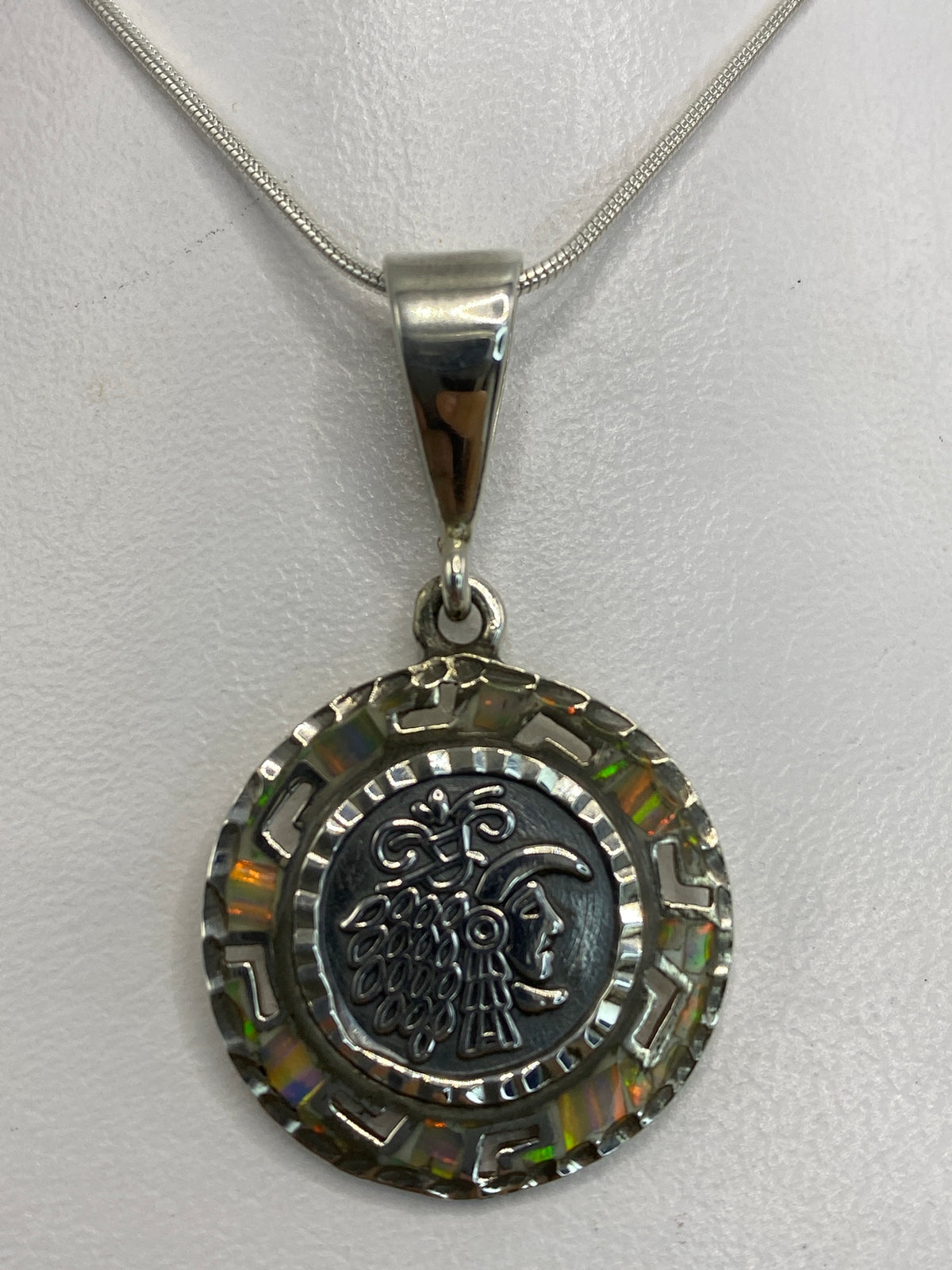 Dije de plata 950 con motivo prehispánico y ópalo multicolor engastado, colgando de cadena plateada