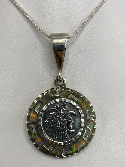 Dije de plata 950 con motivo prehispánico y ópalo multicolor engastado, colgando de cadena plateada